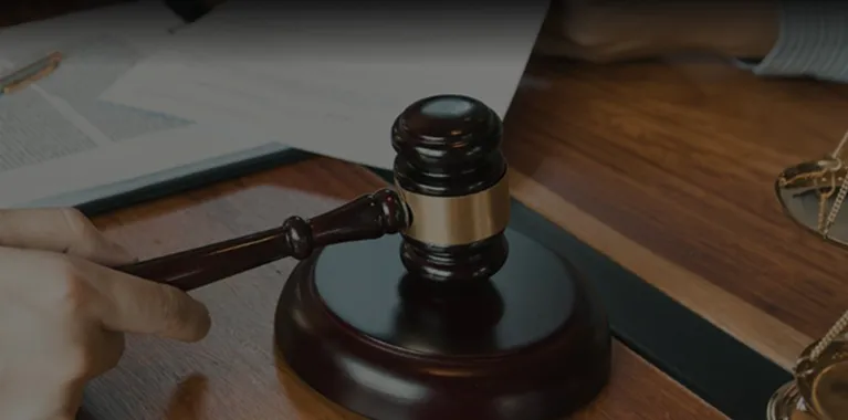 Close-up of a dark wooden judge's gavel held above a sound block on a wooden desk.