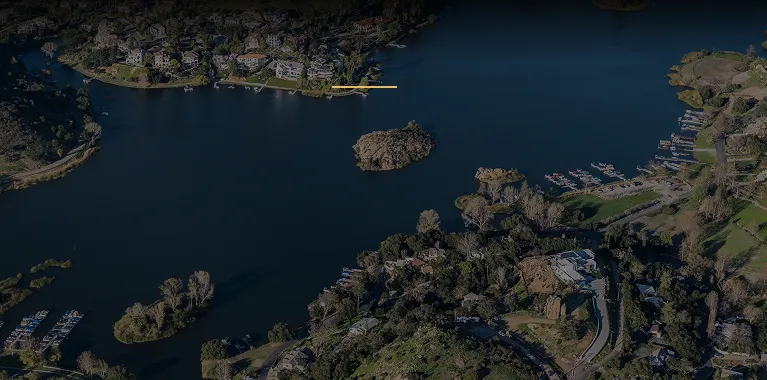Aerial view of a lake surrounded by residential areas, docks, and greenery.