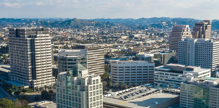 Aerial view of a cityscape with multiple high-rise buildings under a partly cloudy sky.