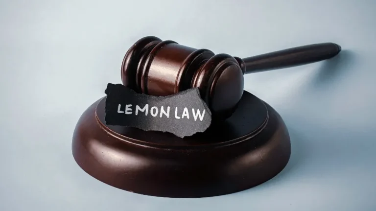 Dark wooden judge's gavel resting on a base with a torn paper labeled "LEMON LAW.