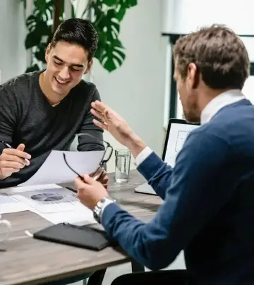 Two men engaged in a business meeting, reviewing documents at a desk.