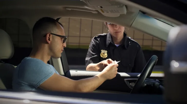 Police officer in uniform checking driver's identification inside a car.